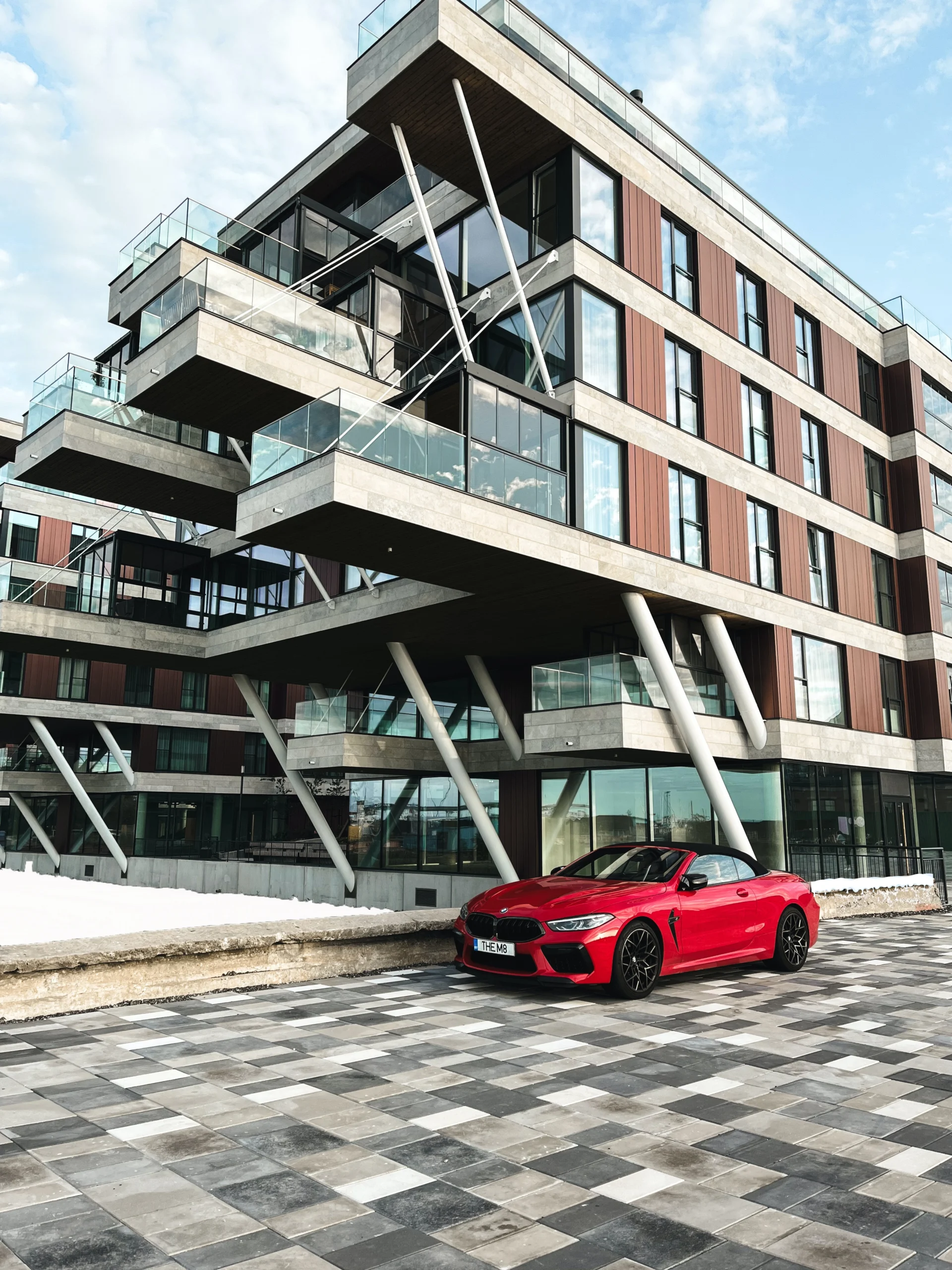 Snow melting condo entrance with red car parked